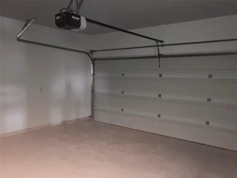 Garage featuring a garage door opener and baseboards