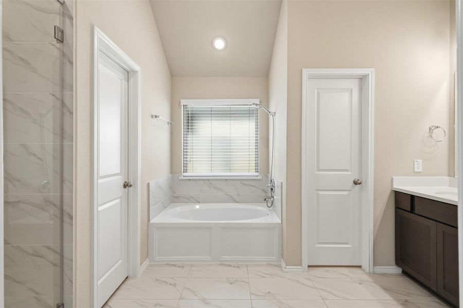 Spa-inspired primary bath featuring dual vanities, a soaking tub, a walk-in glass shower, and elegant designer finishes. Spa-inspired primary bath featuring dual vanities, a soaking tub, a walk-in glass shower, and elegant designer finishes.