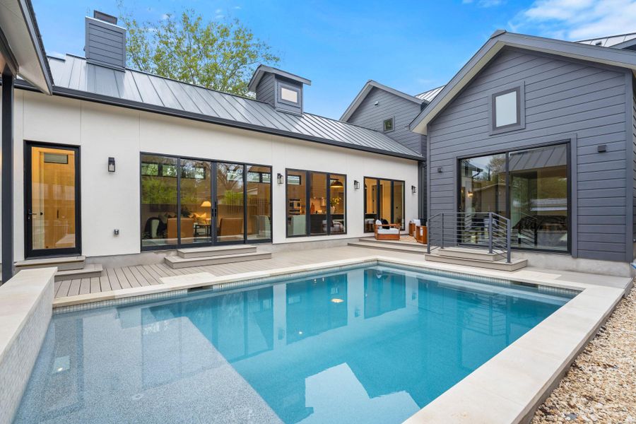 Rear view of property with a standing seam roof, a metal roof, and an outdoor pool