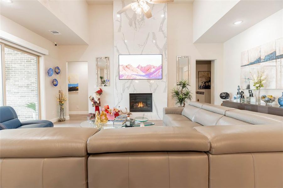 Living room featuring a premium fireplace, a ceiling fan, light wood-type flooring, and recessed lighting
