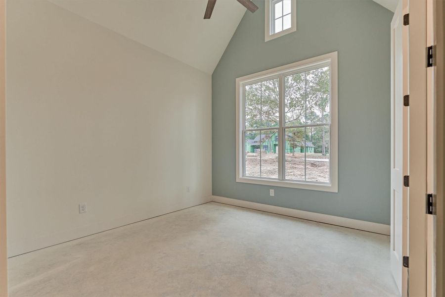 Light-filled bedroom with vaulted ceilings, a soothing accent wall, and peaceful views of the property.
