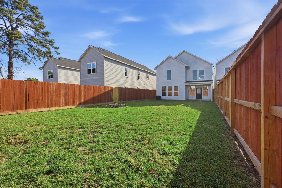 Backyard view facing the house, featuring a covered porch for outdoor dining and relaxation.