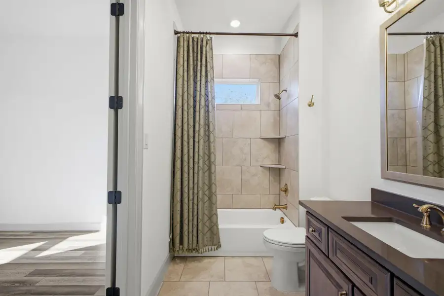 Bathroom with a tub and shower combination featuring tiled walls, built-in shelves, and a window