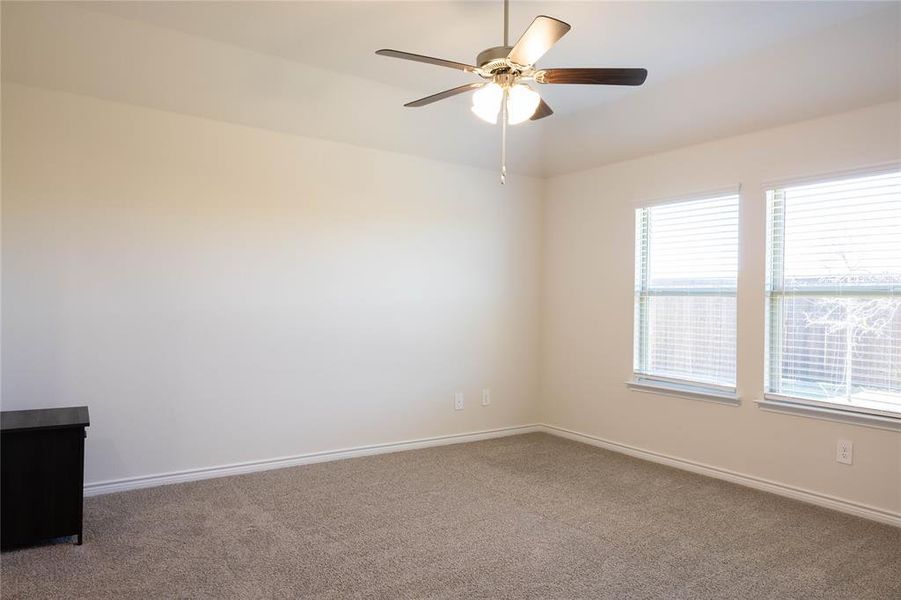 Carpeted empty room with baseboards and a ceiling fan