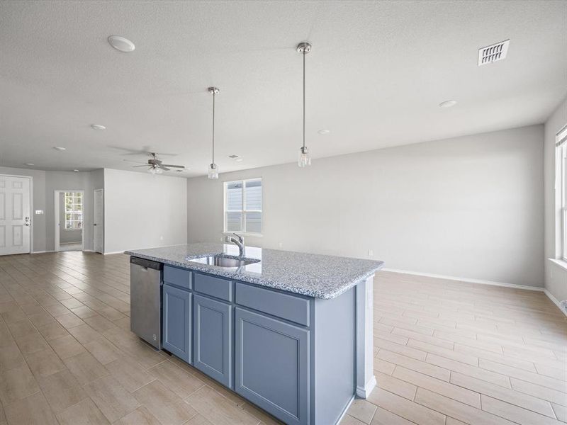 Kitchen featuring open floor plan, light stone countertops, wood finish floors, decorative light fixtures, and stainless steel dishwasher Kitchen featuring open floor plan, light stone countertops, wood finish floors, decorative light fixtures, and stainless steel dishwasher