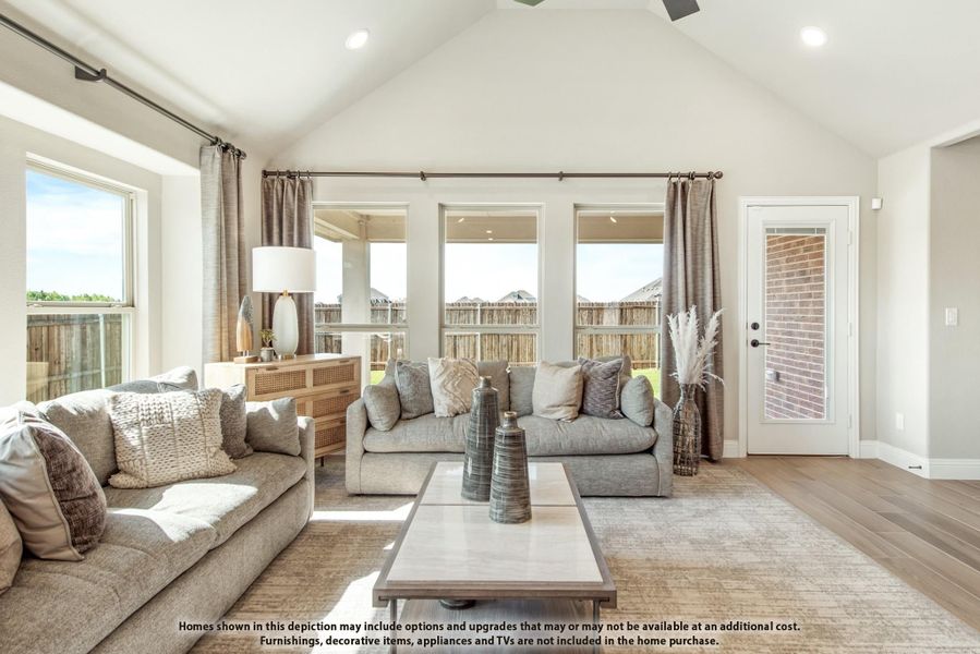 Living room with vaulted ceiling, gray sofas, hardwood floors, and large windows with backyard views