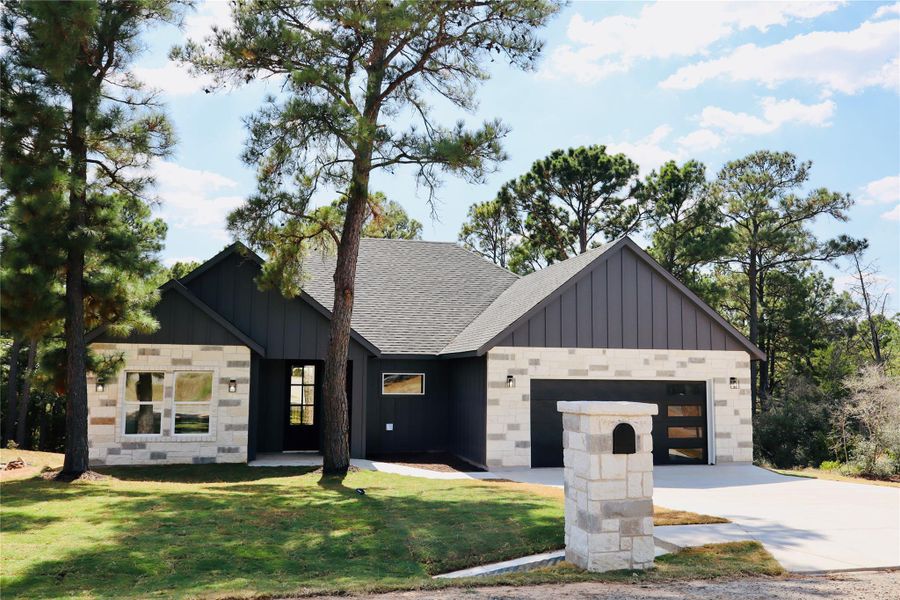 Modern inspired farmhouse with board and batten siding, concrete driveway, a garage, roof with shingles, and a front lawn