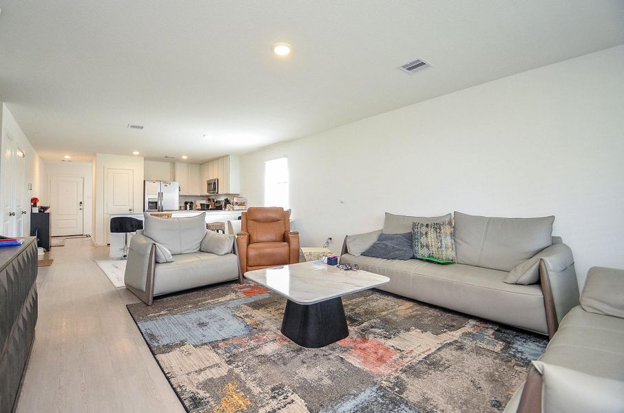 This photo showcases a spacious covered patio with modern outdoor furniture, ceiling fans, and a mounted TV, perfect for entertaining. The area overlooks a well-maintained lawn, providing a private and inviting outdoor living space.
