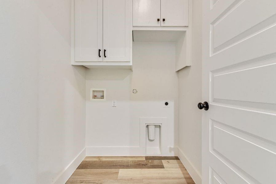 Laundry area featuring gas dryer hookup, light wood-type flooring, cabinet space, washer hookup, and hookup for an electric dryer Laundry area featuring gas dryer hookup, light wood-type flooring, cabinet space, washer hookup, and hookup for an electric dryer