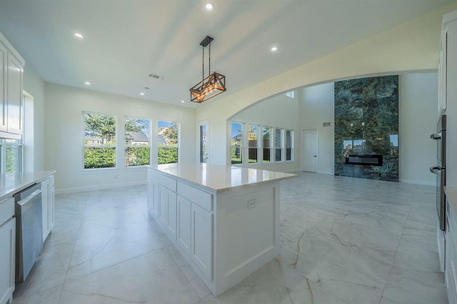Kitchen featuring light marble finish flooring, white cabinetry, a tile fireplace, and recessed lighting Kitchen featuring light marble finish flooring, white cabinetry, a tile fireplace, and recessed lighting