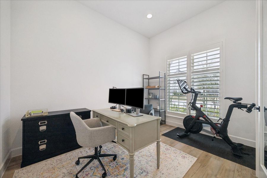 Office space towards the front of the house with plantation shutters and glass French doors.