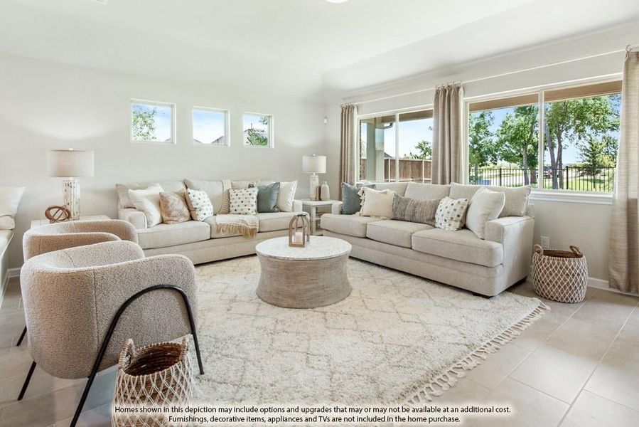 Bright living room with two beige sofas, round coffee table, and large windows overlooking a backyard