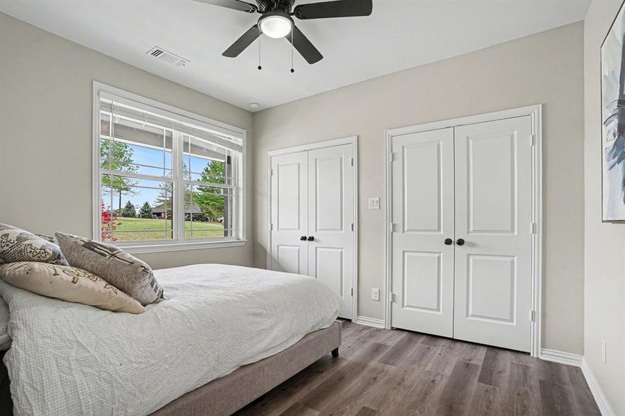 Guest Quarters Bedroom featuring two closets, wood finished floors, and a ceiling fan