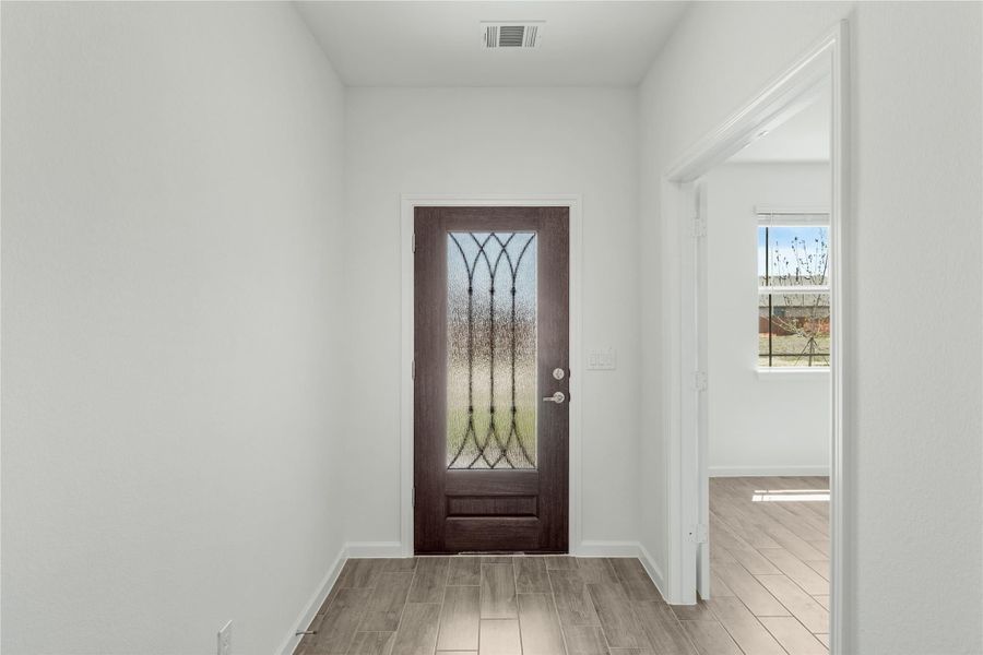 Entryway with dark wood front door featuring decorative glass panel and wood-look tile floors