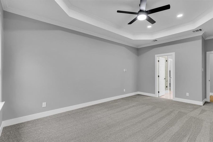 Unfurnished bedroom with light carpet, a raised ceiling, ceiling fan, and ornamental molding