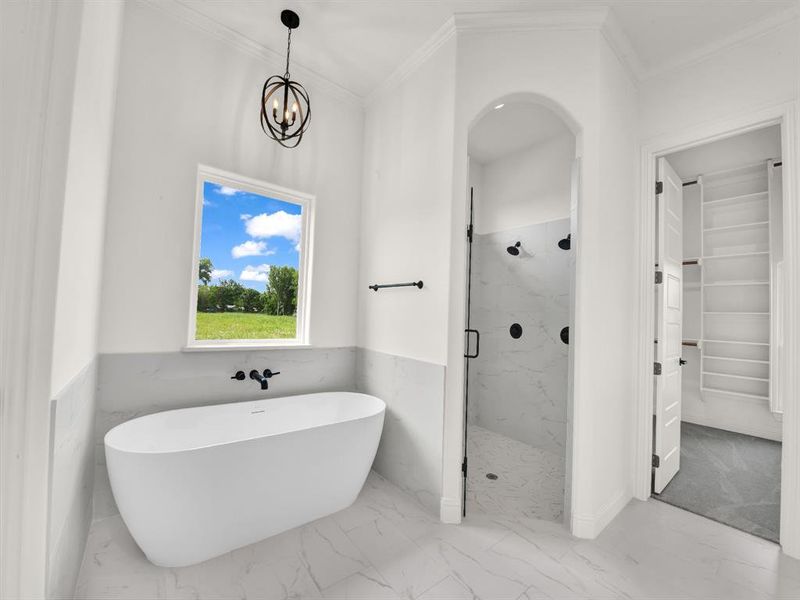 Bathroom with marble finish floors, a marble finish shower, a freestanding tub, ornamental molding, and a chandelier