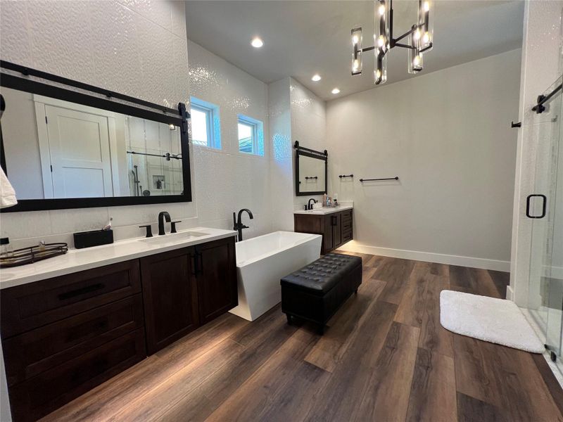 Full bathroom featuring a shower stall, two vanities, a freestanding bath, and recessed lighting and chandelier Full bathroom featuring a shower stall, two vanities, a freestanding bath, and recessed lighting and chandelier