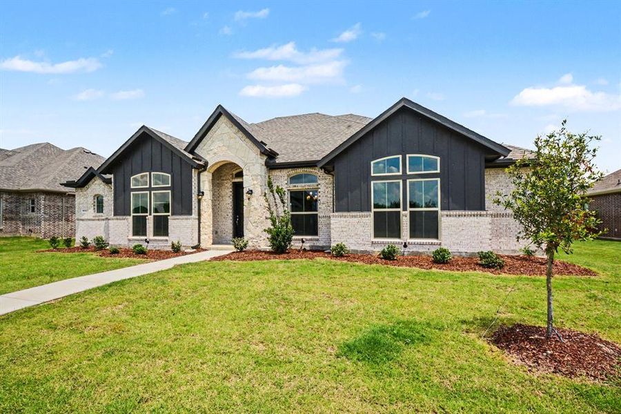 Contemporary single-story residence featuring a light brick facade with dark vertical siding accents Contemporary single-story residence featuring a light brick facade with dark vertical siding accents