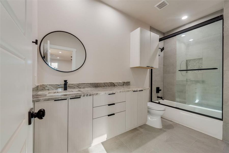 Full bathroom featuring vanity, enclosed tub / shower combo, toilet, and tile patterned floors