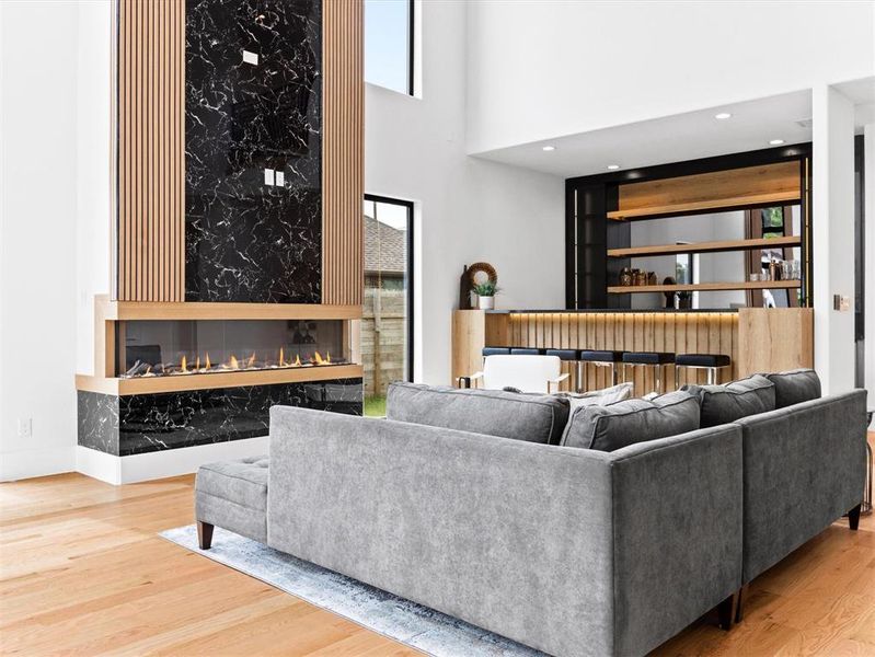 Living room with a towering ceiling, a high end fireplace, and hardwood / wood-style floors