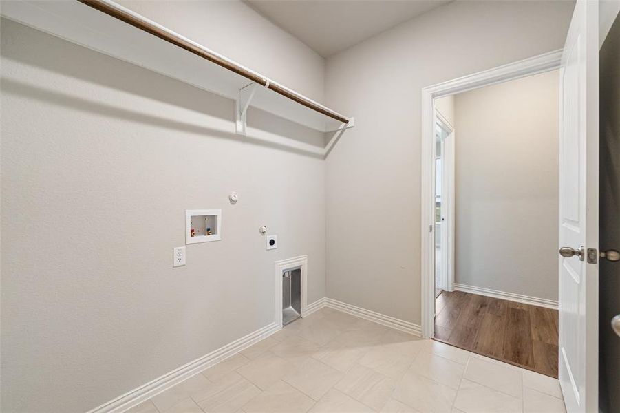 Laundry area with hookup for a gas dryer, washer hookup, electric dryer hookup, and light tile patterned floors