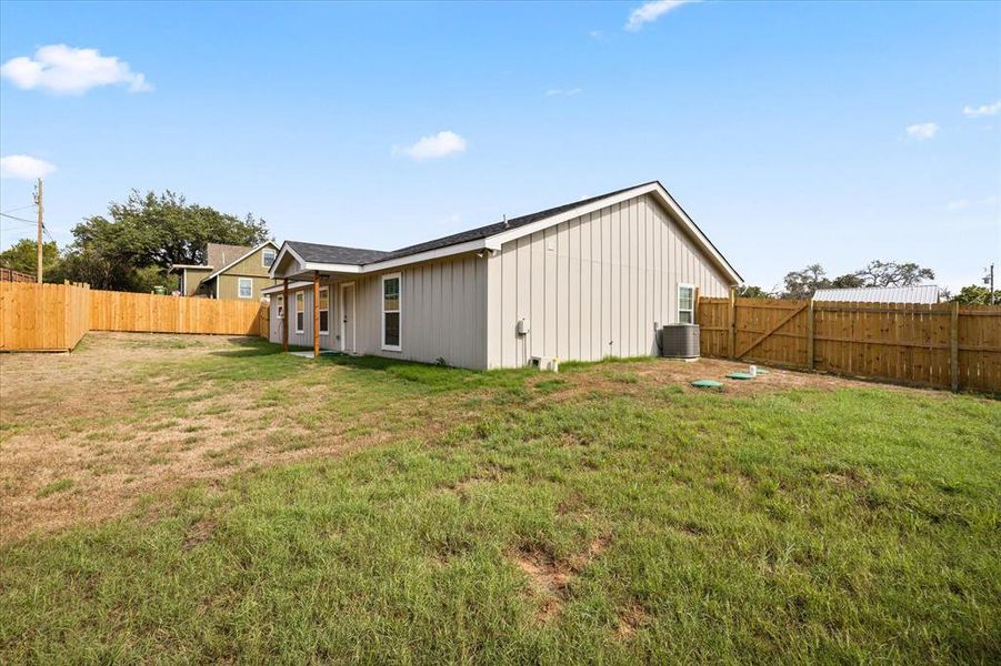 Back of property with a lawn and central air condition unit