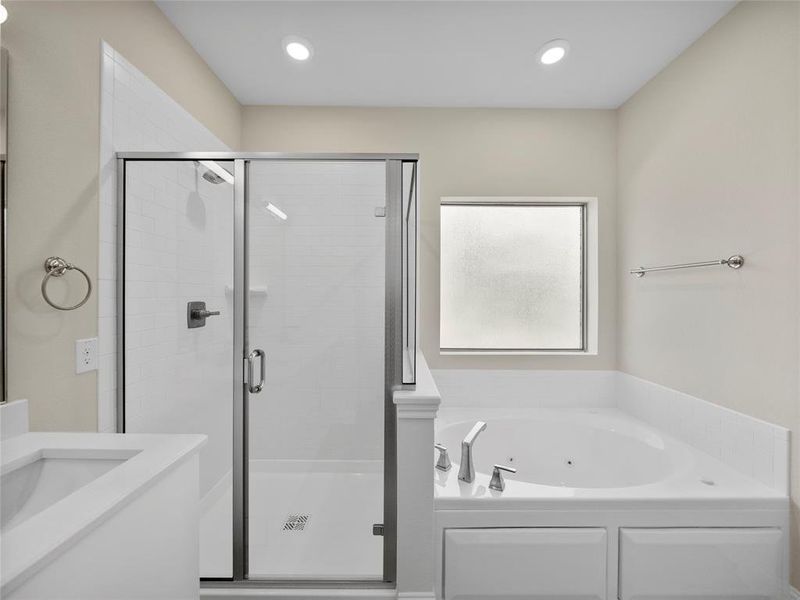 Bathroom featuring a stall shower, a jetted tub, vanity, and recessed lighting