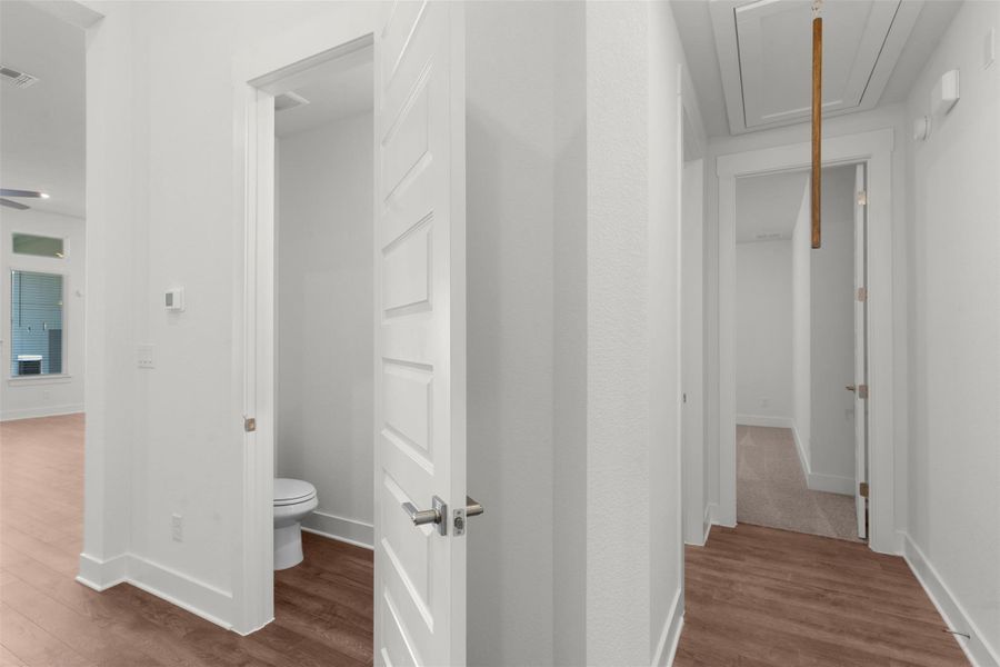 Hall with attic access and light wood-style flooring
