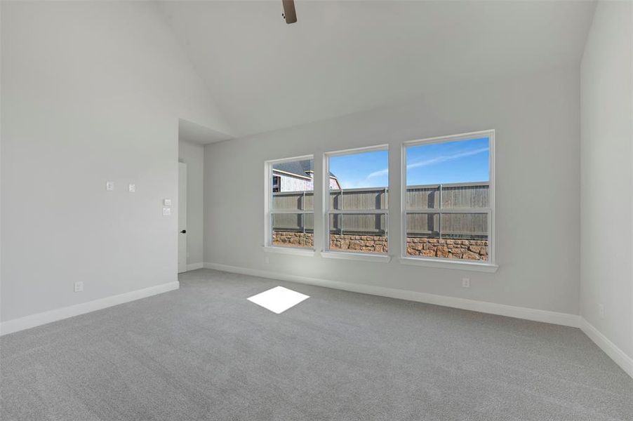 Unfurnished room featuring light carpet, vaulted ceiling, and ceiling fan