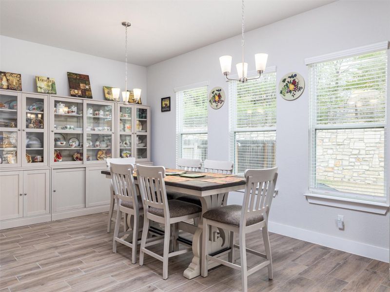Dining room with suspended lighting and wood tiled floors