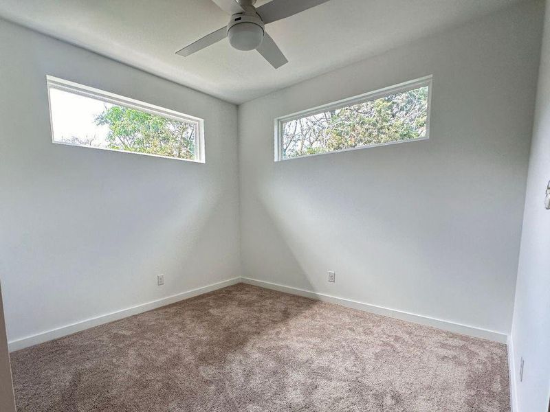 An airy bedroom with dual transom windows and plush carpeting creates a tranquil retreat. An airy bedroom with dual transom windows and plush carpeting creates a tranquil retreat.