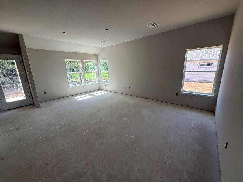 Empty room with healthy amount of natural light, vaulted ceiling, and unfinished concrete flooring