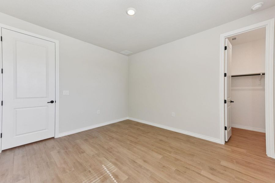 Unfurnished bedroom with a spacious closet, light wood finished floors, and recessed lighting