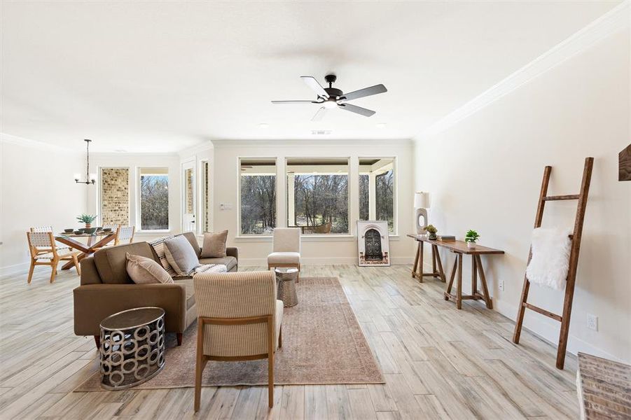 Living area featuring ornamental molding, light wood-style flooring, a ceiling fan, and a chandelier