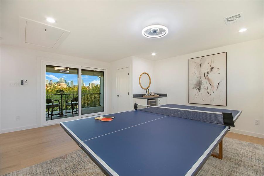 Recreation room featuring light wood-style floors, recessed lighting, a skyline view, wine cooler, and attic access