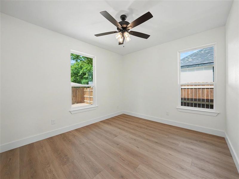 Bright interior room featuring wood-finish flooring, white walls, and white trim Bright interior room featuring wood-finish flooring, white walls, and white trim