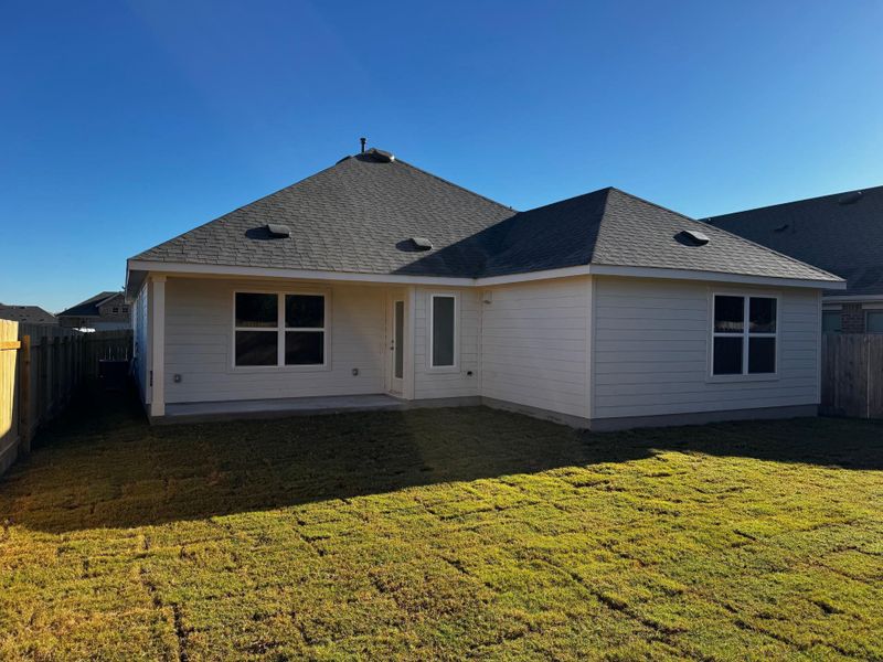 Rear view of property with a fenced backyard, a patio area, and roof with shingles