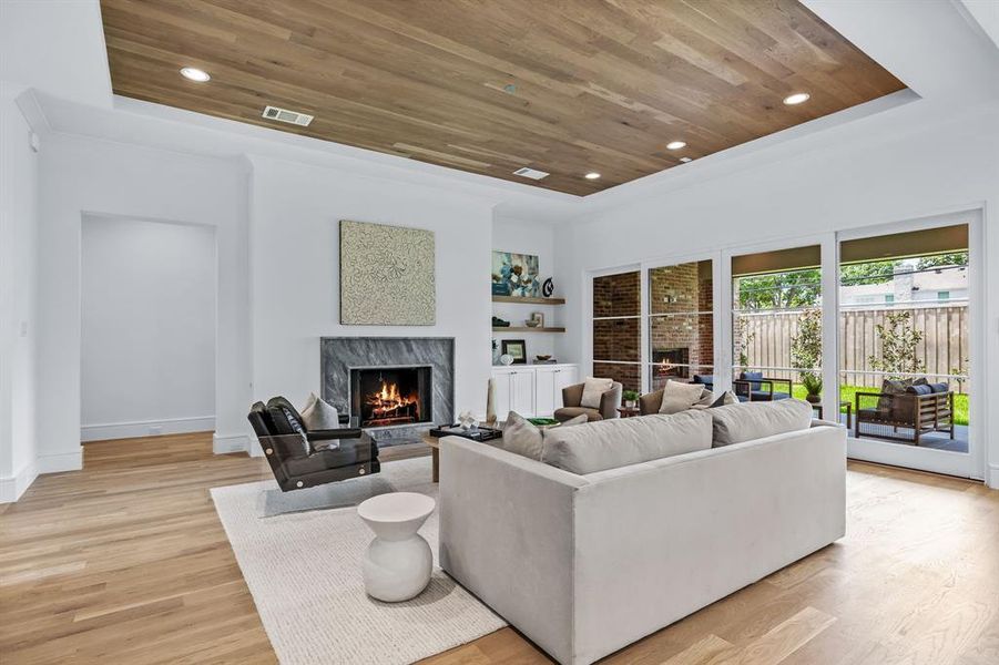 Living room featuring light hardwood / wood-style floors, a fireplace, wood ceiling, and built in features