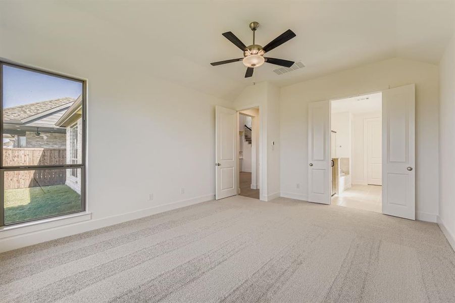 Unfurnished bedroom with light carpet, lofted ceiling, ceiling fan, and connected bathroom Unfurnished bedroom with light carpet, lofted ceiling, ceiling fan, and connected bathroom