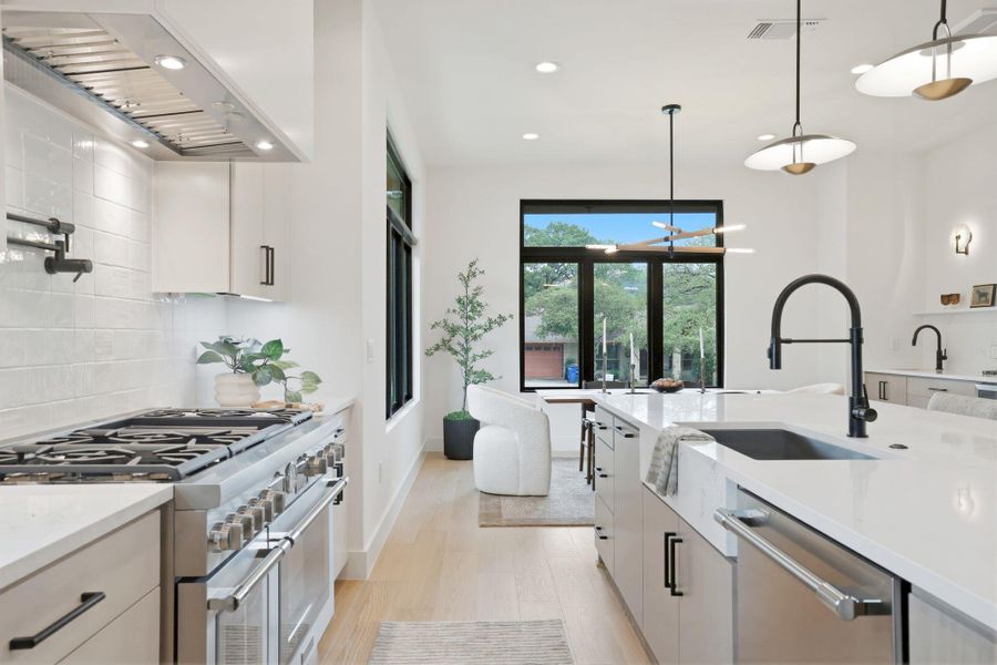 Contemporary kitchen featuring a professional-grade range, full-height tile backsplash, and light wood-finish flooring