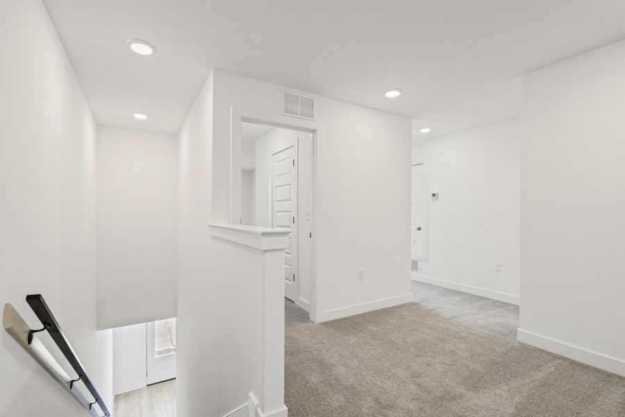 Hallway featuring an upstairs landing, recessed lighting, and light colored carpet