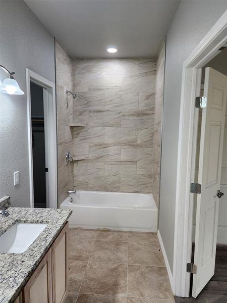 Bathroom with tile patterned flooring, vanity, and tiled shower / bath