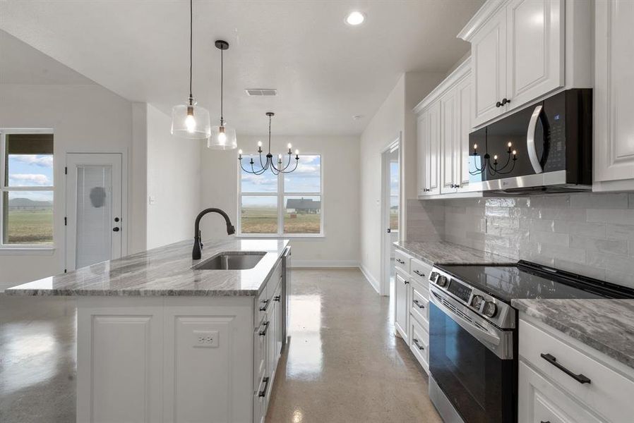 Kitchen featuring stainless steel appliances, sink, an island with sink, and plenty of natural light