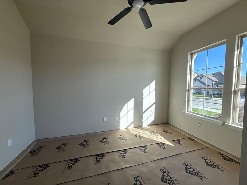Empty room featuring ceiling fan and vaulted ceiling