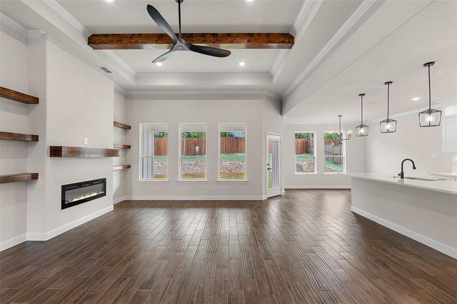 Unfurnished living room with sink, crown molding, dark hardwood / wood-style floors, beam ceiling, and ceiling fan