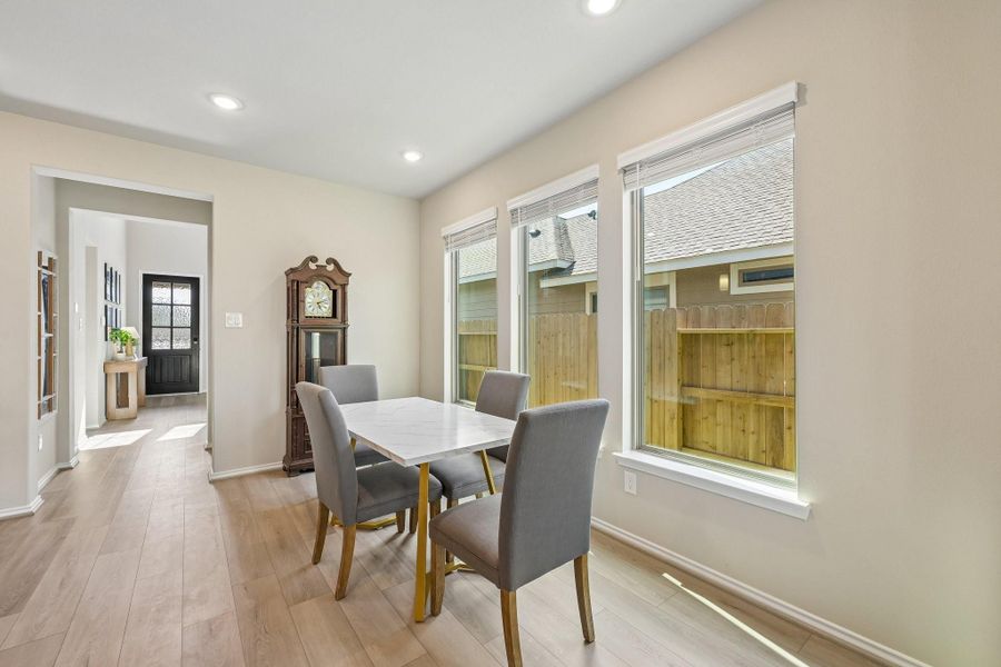 Bright dining area with large windows, elegant grandfather clock, and modern table, creating a welcoming atmosphere.