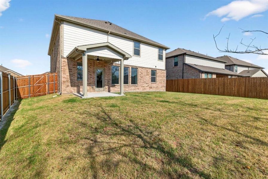 Back of property with a patio, a fenced backyard, brick siding, and ceiling fan