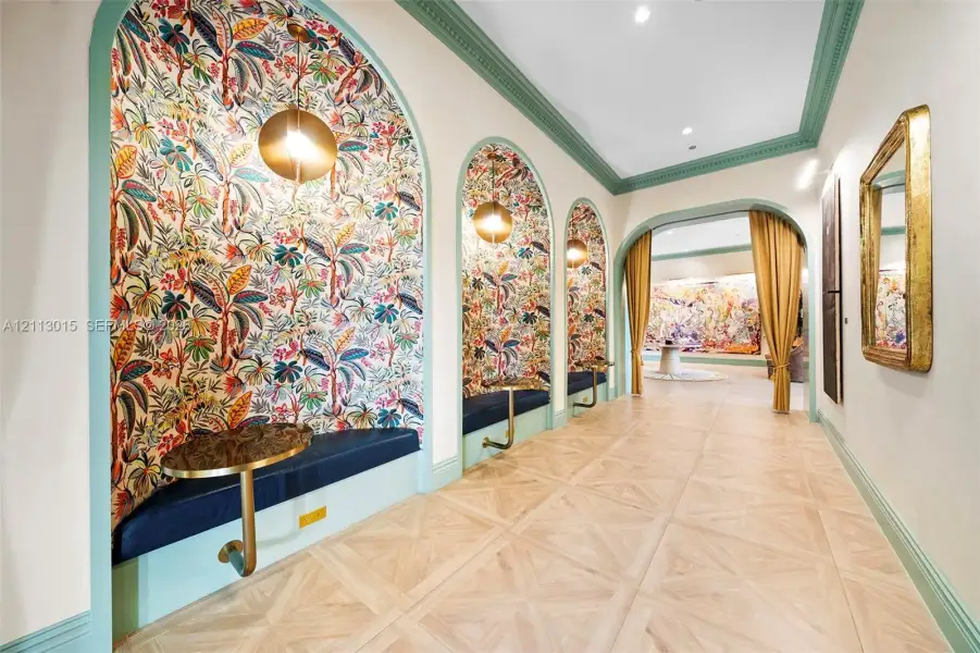 Hallway featuring arched recessed alcoves with botanical wall coverings, built-in upholstered benches, gold-toned metallic accents, and intricate parquet wood-finish flooring