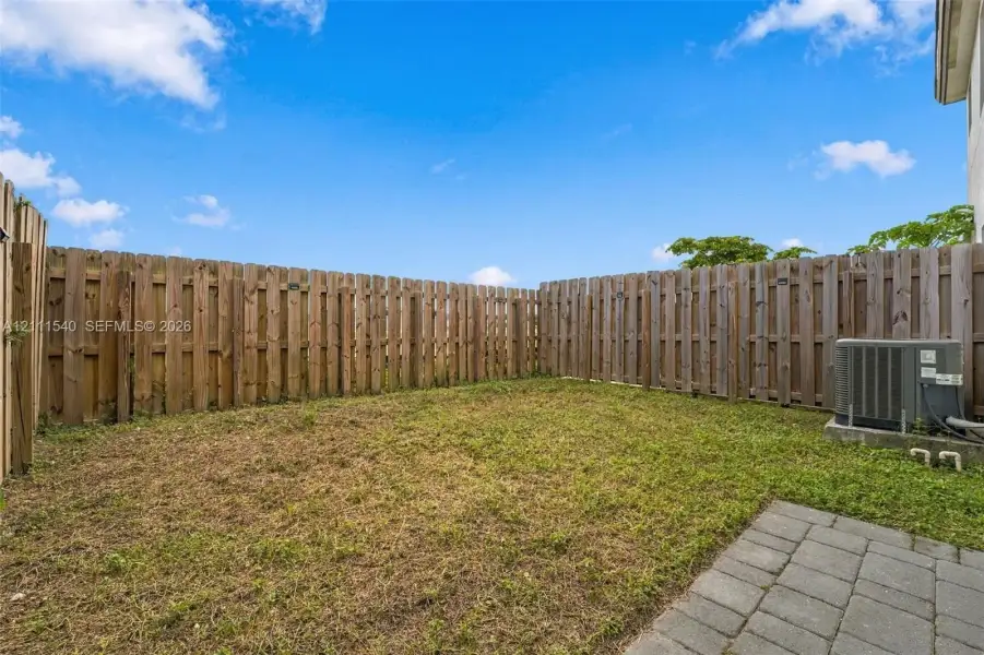 Fenced backyard featuring a grass lawn and stone paver patio
