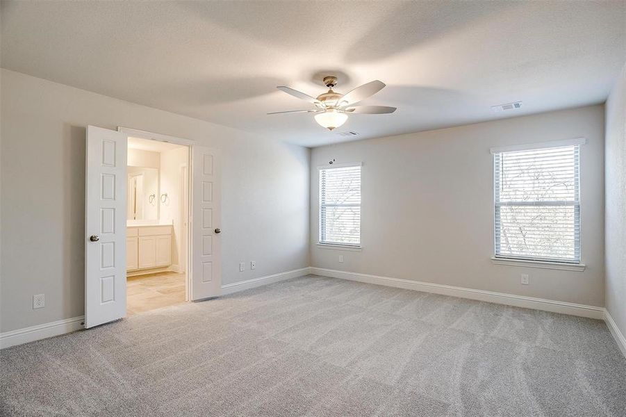 Empty room featuring light colored carpet, ceiling fan, visible vents, and baseboards